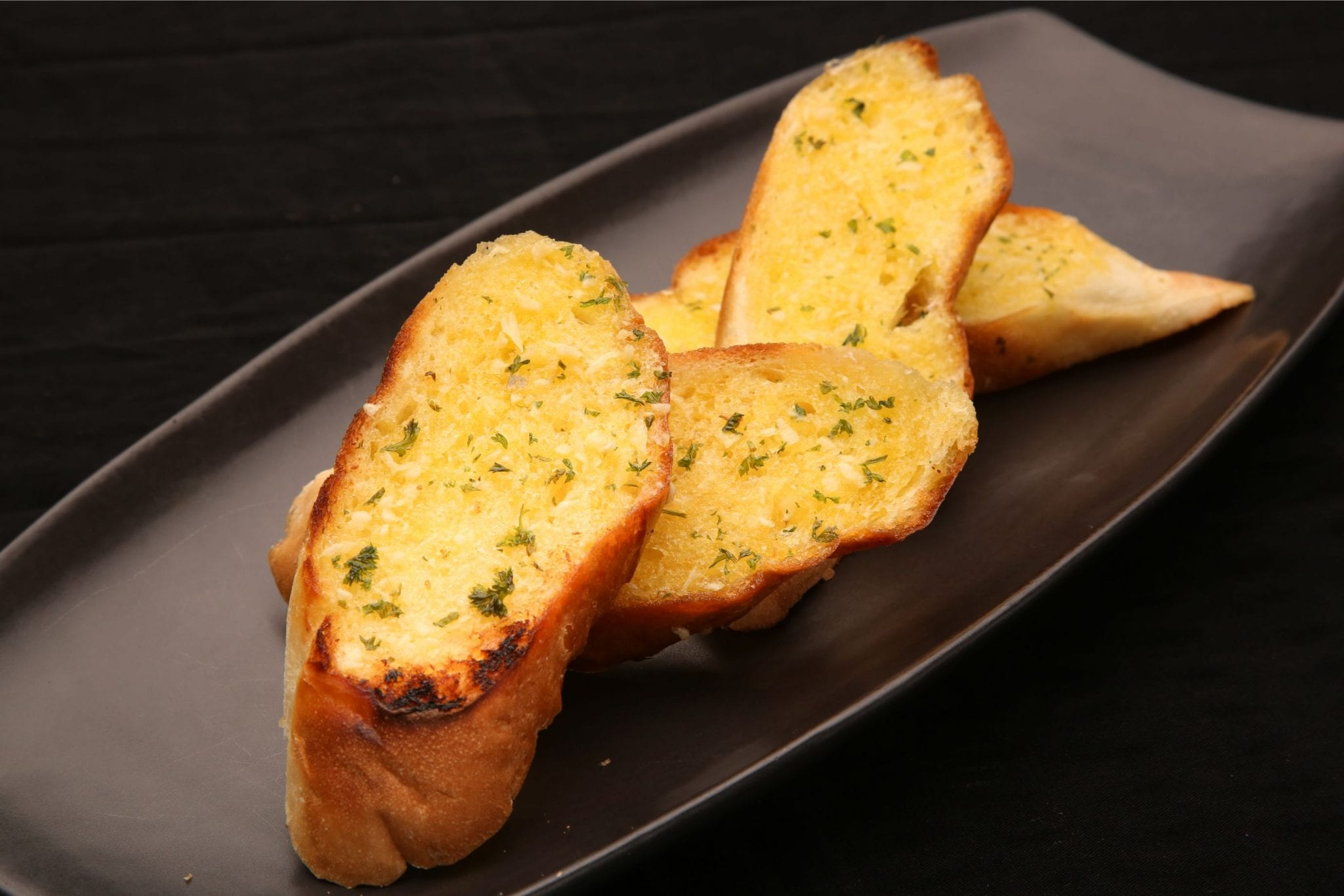 slices of weed garlic bread on a black abstract plate