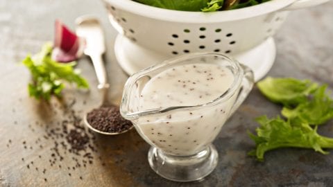Cannabis poppyseed salad dressing only black surface with leaves and poppy seeds in the