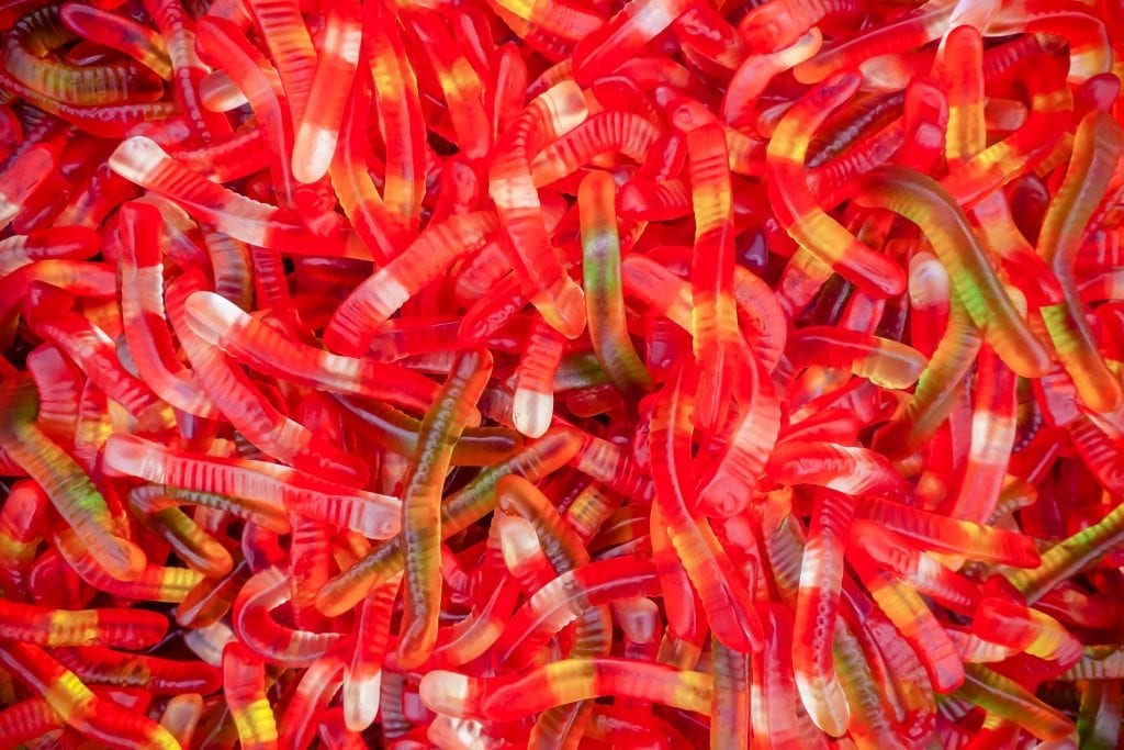 A large pile of cannabis infused gummy worms piled on top of each other. Bright red gummy candies
